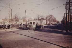 green and white steetcar on tracks with houses in background