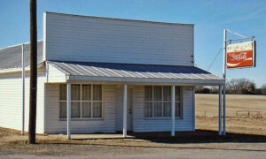 small white building with covered porch coke sign