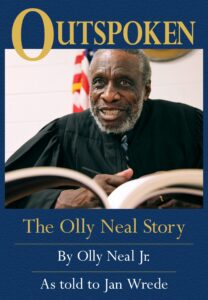 black man with white beard in judges robe with book open in front of him