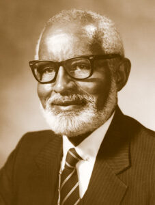 older Black man with beard glasses suit and tie