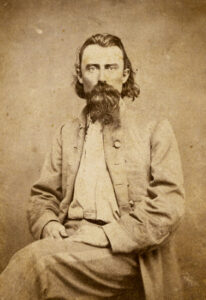 thin white man with long beard and slicked back hair in military suit