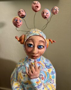 sculpture of a person with five small heads protruding from their head