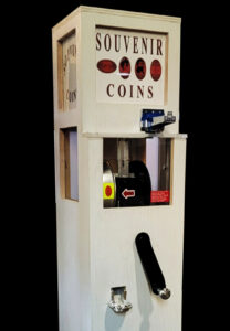 machine with coin slot and crank and words "souvenir coins"