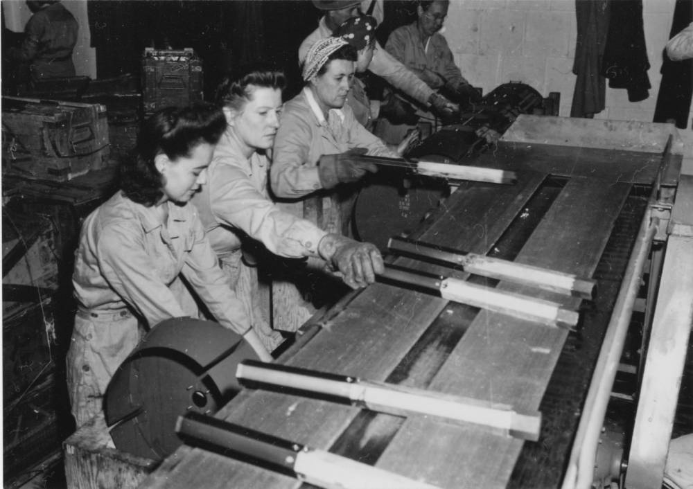 white women in coveralls moving objects on a conveyer belt