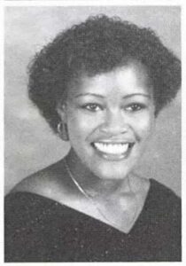 young black woman with curly hair smiling in yearbook photo