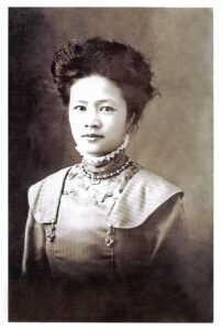 an Asian woman with her hair in an up do and a high necked dress