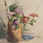Cylindrical vase with flowers on a table with a small bowl