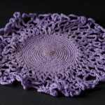 Round crocheted doily made from purple cotton thread
