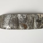 Piece of steel with rounded corners and the initials "M. R. V."