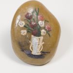 White vase holding flowers painted on a stone