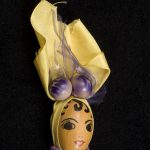 Woman's visage is painted on a pecan with a piece of yellow cloth as a head scarf
