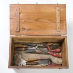 Large wooden box open with a variety of tools and rags
