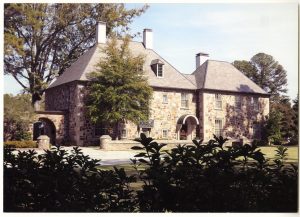 Multistory house with stone walls and bushes in the foreground