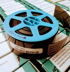 blue reel of microfilm on top of many boxes of microfilm
