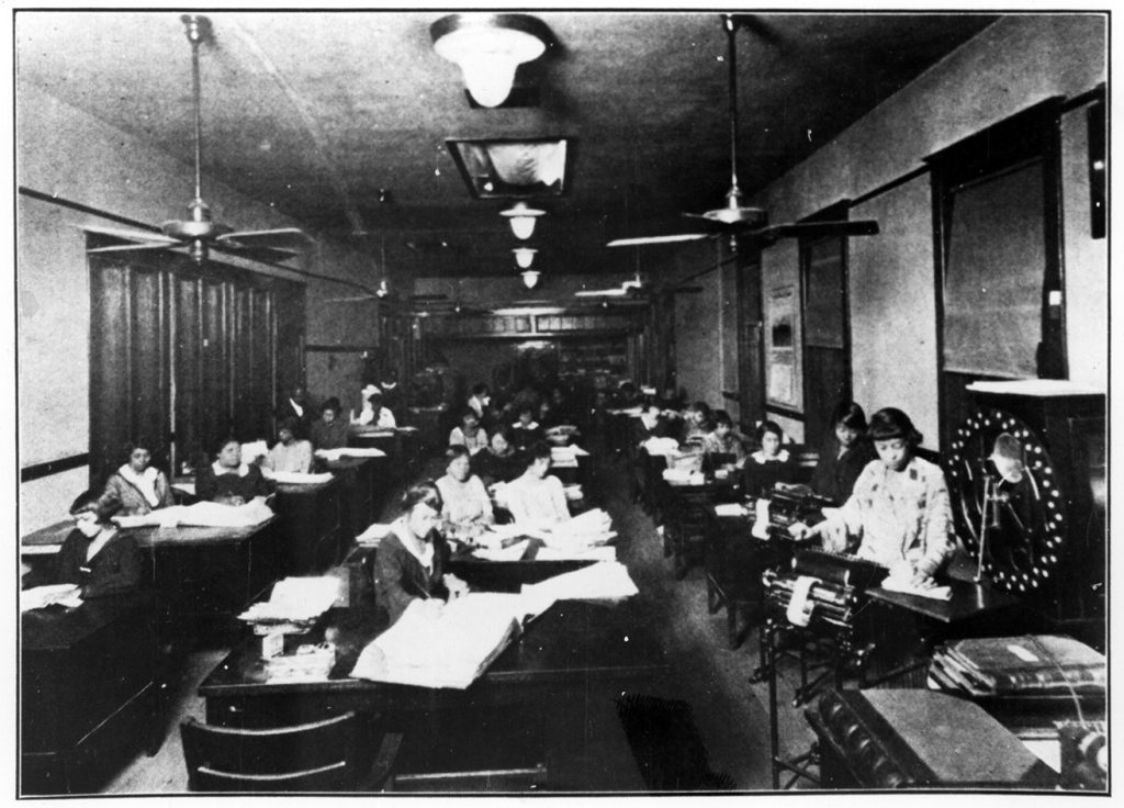 African-American women working at their desks in office under ceiling fans