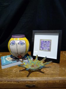 Painted vase on books with picture frame and ceramic tray on display
