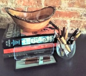 Ceramic bowl on stack of books and pens on display