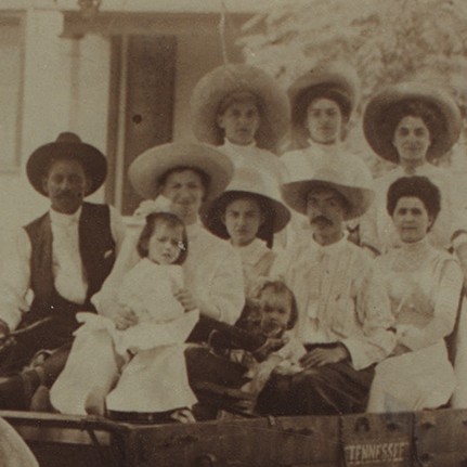 Seven women and girls and two men sitting in a wagon