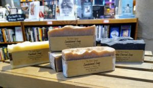 Bars of soap with labels on wooden display with bookshelf in the background