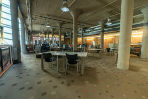 Desks with chairs on carpet in research room with columns