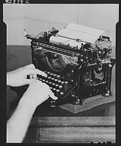 Person's hands using a typewriter on desk