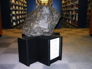 large grayish rock sitting on a black pedestal 