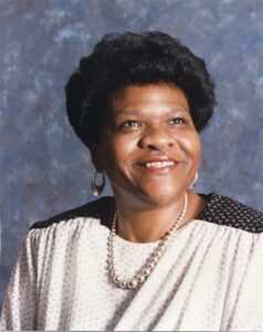 smiling African American woman with earrings a pearl necklace and a polk dot top